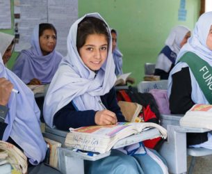a classroom of young women wearing headscarves with books and posters