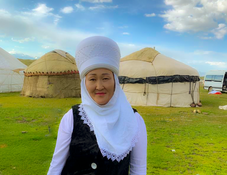 Zuura Ibraimova stands in front of her yurts in traditional dress.
