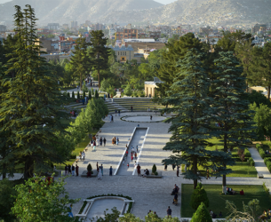 People are shown walking in a park with a city in the background