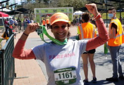 AKF USA supporter Farzana holds up her medal while wearing a racing bib