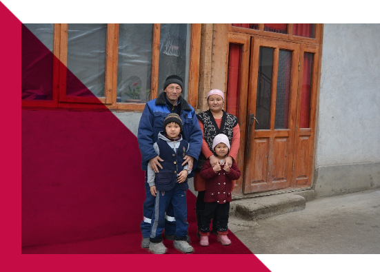 A man, woman, and two young children wearing winter clothes stand outside of a building in the Kyrgyz Republic