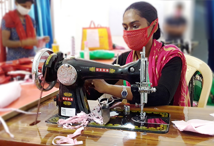 Girl wearing a face mask uses a sewing machine in a youth skills development center