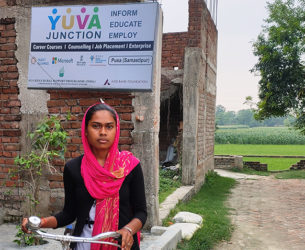 Girl stands with bike in front of a youth skills development center