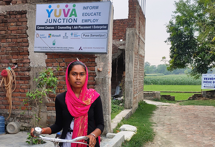 Girl stands with bike in front of a youth skills development center