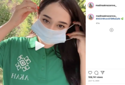 An Instagram screenshot shows a video frame of a woman putting a mask on over her nose and mouth. The Instagram caption is #AKAH#covid19#besafe 🌿