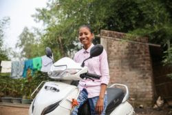 Girl smiles as she sits on a scooter