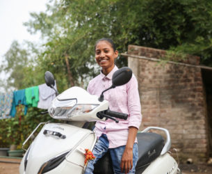 Girl smiles as she sits on a scooter