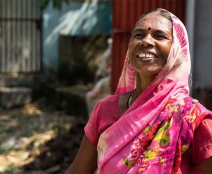 A woman wearing a pink sari smiles.