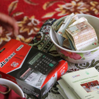 A calculator, bowl of money, and record book are used by the community-based savings group.