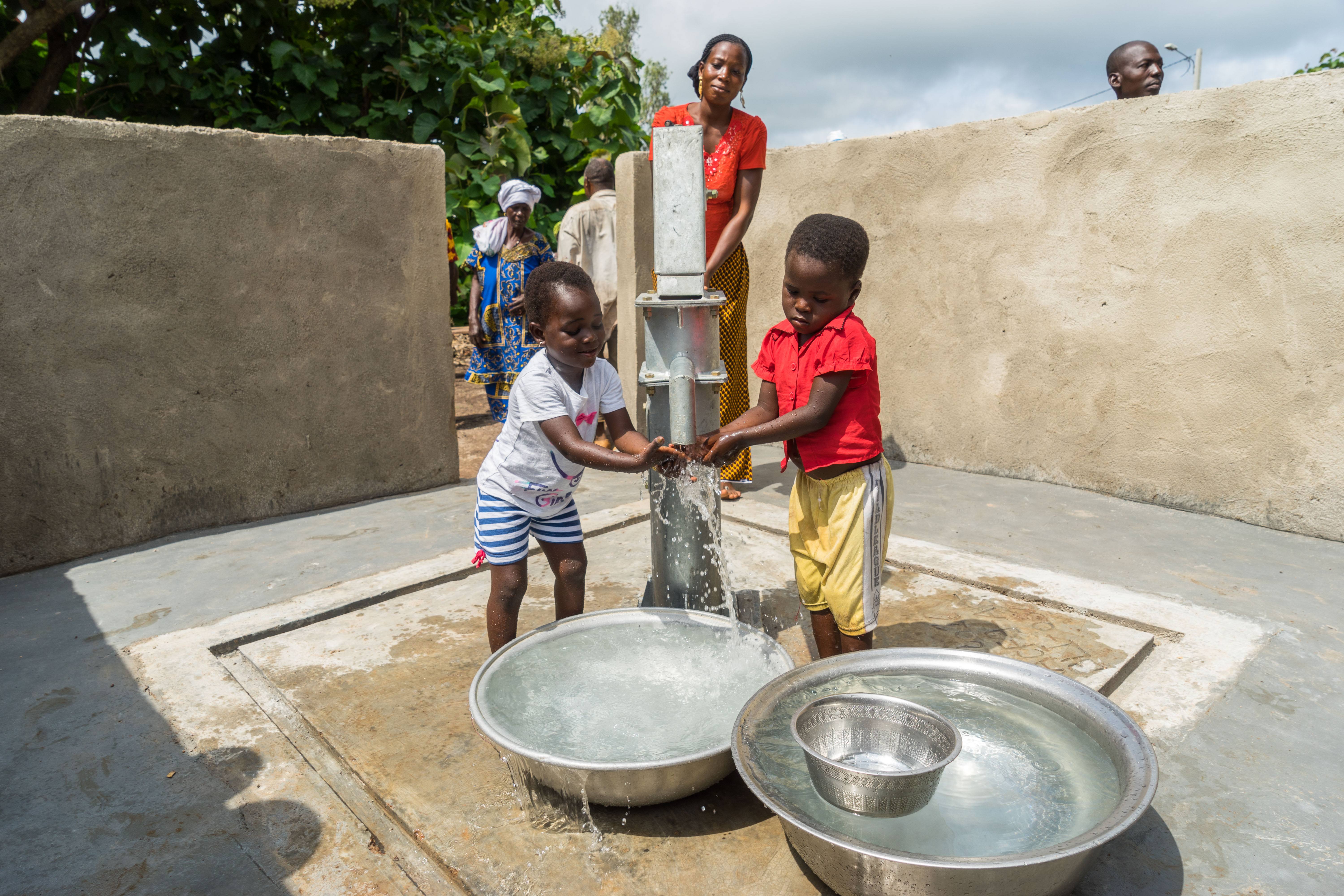 A mother and her children using a water pump built with the support of the Aga Khan Foundation and Ivoire Coton in Ouazomon, Cote de Ivoire