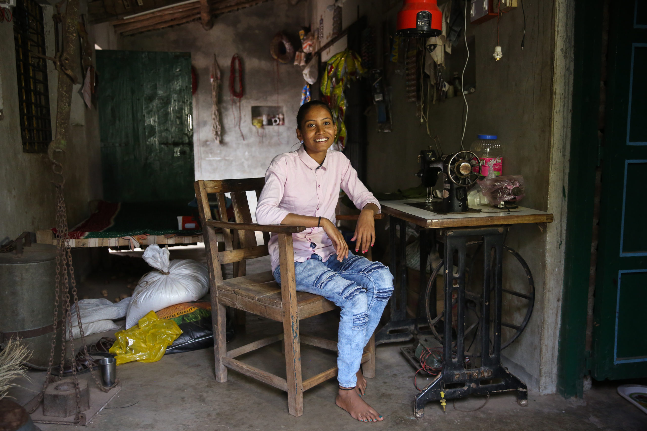 Girl sits in her home in front on a sewing machine